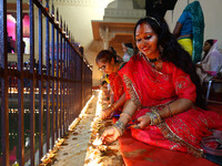 A woman lights earthen lamps at the Shrine Galtaji temple holy pond 'kund' as part of the Deep Mahotsav celebration on the eve of Dev Deepaw...