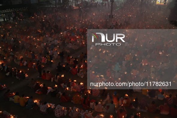 Hindu devotees sit together in front of oil lamps and pray to Shri Shri Loknath Brahmachari, a Hindu saint and philosopher, as they observe...