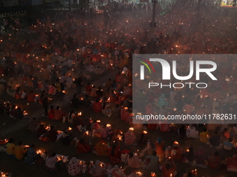 Hindu devotees sit together in front of oil lamps and pray to Shri Shri Loknath Brahmachari, a Hindu saint and philosopher, as they observe...