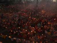 Hindu devotees sit together in front of oil lamps and pray to Shri Shri Loknath Brahmachari, a Hindu saint and philosopher, as they observe...