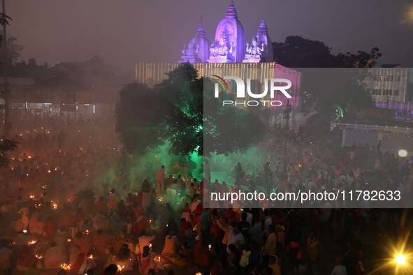 Hindu devotees sit together in front of oil lamps and pray to Shri Shri Loknath Brahmachari, a Hindu saint and philosopher, as they observe...