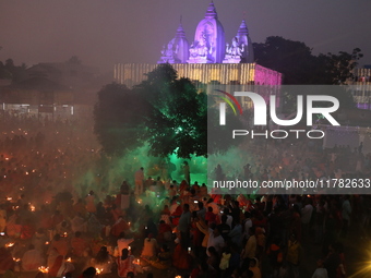 Hindu devotees sit together in front of oil lamps and pray to Shri Shri Loknath Brahmachari, a Hindu saint and philosopher, as they observe...