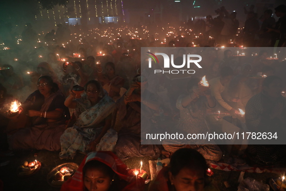 Hindu devotees sit together in front of oil lamps and pray to Shri Shri Loknath Brahmachari, a Hindu saint and philosopher, as they observe...