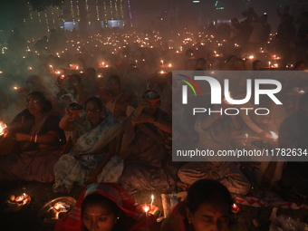 Hindu devotees sit together in front of oil lamps and pray to Shri Shri Loknath Brahmachari, a Hindu saint and philosopher, as they observe...