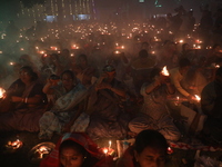 Hindu devotees sit together in front of oil lamps and pray to Shri Shri Loknath Brahmachari, a Hindu saint and philosopher, as they observe...