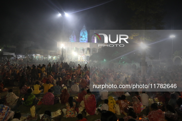 Hindu devotees sit together in front of oil lamps and pray to Shri Shri Loknath Brahmachari, a Hindu saint and philosopher, as they observe...