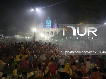 Hindu devotees sit together in front of oil lamps and pray to Shri Shri Loknath Brahmachari, a Hindu saint and philosopher, as they observe...