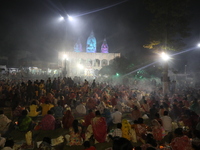 Hindu devotees sit together in front of oil lamps and pray to Shri Shri Loknath Brahmachari, a Hindu saint and philosopher, as they observe...