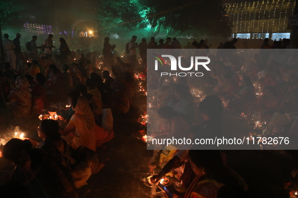 Hindu devotees sit together in front of oil lamps and pray to Shri Shri Loknath Brahmachari, a Hindu saint and philosopher, as they observe...