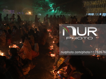 Hindu devotees sit together in front of oil lamps and pray to Shri Shri Loknath Brahmachari, a Hindu saint and philosopher, as they observe...