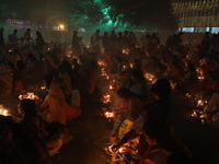 Hindu devotees sit together in front of oil lamps and pray to Shri Shri Loknath Brahmachari, a Hindu saint and philosopher, as they observe...