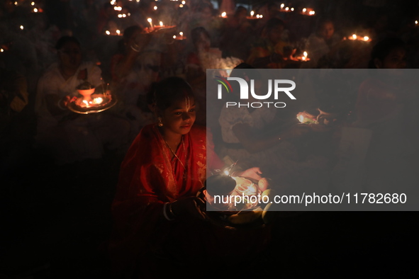 Hindu devotees sit together in front of oil lamps and pray to Shri Shri Loknath Brahmachari, a Hindu saint and philosopher, as they observe...