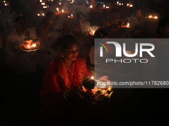 Hindu devotees sit together in front of oil lamps and pray to Shri Shri Loknath Brahmachari, a Hindu saint and philosopher, as they observe...