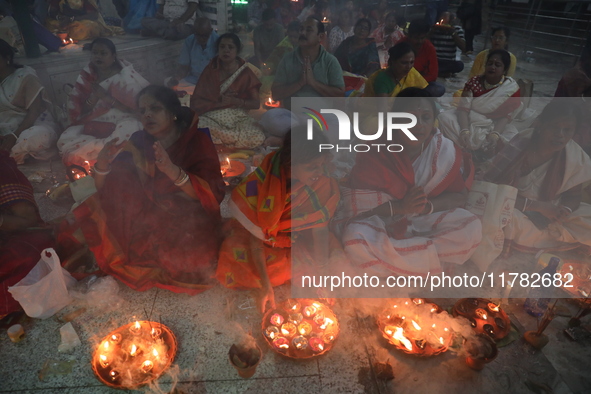 Hindu devotees sit together in front of oil lamps and pray to Shri Shri Loknath Brahmachari, a Hindu saint and philosopher, as they observe...