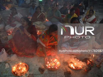 Hindu devotees sit together in front of oil lamps and pray to Shri Shri Loknath Brahmachari, a Hindu saint and philosopher, as they observe...