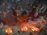 Hindu devotees sit together in front of oil lamps and pray to Shri Shri Loknath Brahmachari, a Hindu saint and philosopher, as they observe...