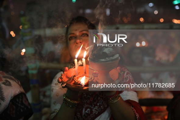 Hindu devotees sit together in front of oil lamps and pray to Shri Shri Loknath Brahmachari, a Hindu saint and philosopher, as they observe...