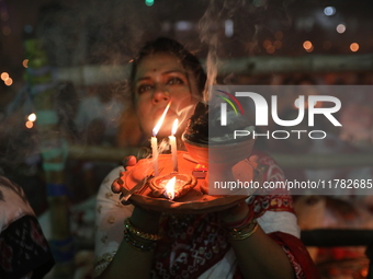 Hindu devotees sit together in front of oil lamps and pray to Shri Shri Loknath Brahmachari, a Hindu saint and philosopher, as they observe...