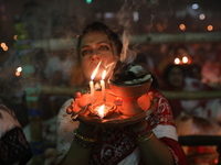 Hindu devotees sit together in front of oil lamps and pray to Shri Shri Loknath Brahmachari, a Hindu saint and philosopher, as they observe...