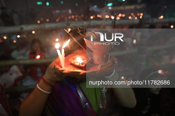 Hindu devotees sit together in front of oil lamps and pray to Shri Shri Loknath Brahmachari, a Hindu saint and philosopher, as they observe...