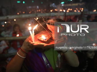 Hindu devotees sit together in front of oil lamps and pray to Shri Shri Loknath Brahmachari, a Hindu saint and philosopher, as they observe...