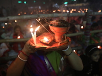 Hindu devotees sit together in front of oil lamps and pray to Shri Shri Loknath Brahmachari, a Hindu saint and philosopher, as they observe...