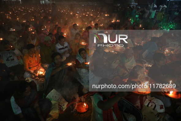 Hindu devotees sit together in front of oil lamps and pray to Shri Shri Loknath Brahmachari, a Hindu saint and philosopher, as they observe...