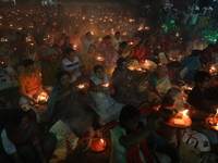 Hindu devotees sit together in front of oil lamps and pray to Shri Shri Loknath Brahmachari, a Hindu saint and philosopher, as they observe...