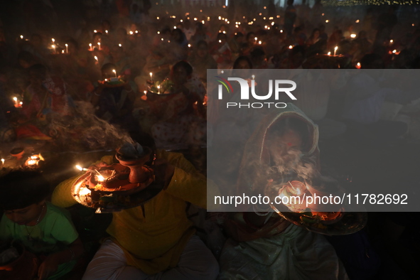 Hindu devotees sit together in front of oil lamps and pray to Shri Shri Loknath Brahmachari, a Hindu saint and philosopher, as they observe...