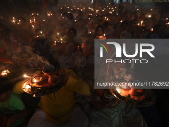 Hindu devotees sit together in front of oil lamps and pray to Shri Shri Loknath Brahmachari, a Hindu saint and philosopher, as they observe...