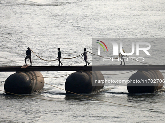 Labourers build a floating pontoon bridge across the river Ganges for devotees ahead of the upcoming Maha Kumbh 2025 festival in Prayagraj,...