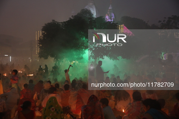 Hindu devotees sit together in front of oil lamps and pray to Shri Shri Loknath Brahmachari, a Hindu saint and philosopher, as they observe...