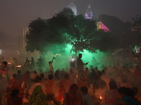 Hindu devotees sit together in front of oil lamps and pray to Shri Shri Loknath Brahmachari, a Hindu saint and philosopher, as they observe...