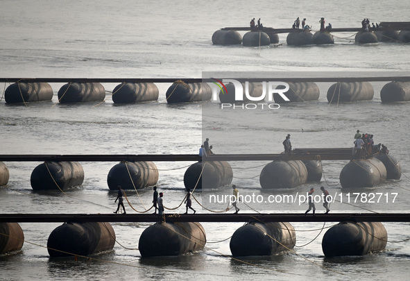 Labourers build a floating pontoon bridge across the river Ganges for devotees ahead of the upcoming Maha Kumbh 2025 festival in Prayagraj,...