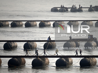 Labourers build a floating pontoon bridge across the river Ganges for devotees ahead of the upcoming Maha Kumbh 2025 festival in Prayagraj,...