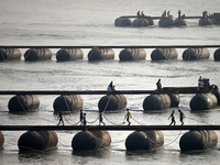 Labourers build a floating pontoon bridge across the river Ganges for devotees ahead of the upcoming Maha Kumbh 2025 festival in Prayagraj,...