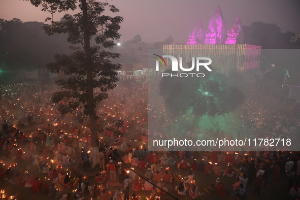 Hindu devotees sit together in front of oil lamps and pray to Shri Shri Loknath Brahmachari, a Hindu saint and philosopher, as they observe...