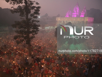 Hindu devotees sit together in front of oil lamps and pray to Shri Shri Loknath Brahmachari, a Hindu saint and philosopher, as they observe...