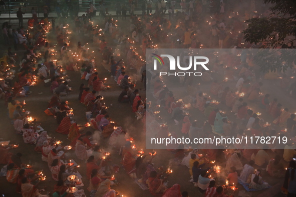 Hindu devotees sit together in front of oil lamps and pray to Shri Shri Loknath Brahmachari, a Hindu saint and philosopher, as they observe...