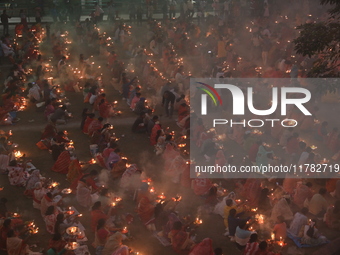 Hindu devotees sit together in front of oil lamps and pray to Shri Shri Loknath Brahmachari, a Hindu saint and philosopher, as they observe...