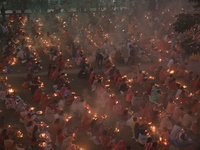 Hindu devotees sit together in front of oil lamps and pray to Shri Shri Loknath Brahmachari, a Hindu saint and philosopher, as they observe...