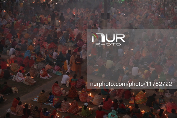 Hindu devotees sit together in front of oil lamps and pray to Shri Shri Loknath Brahmachari, a Hindu saint and philosopher, as they observe...