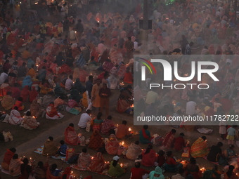 Hindu devotees sit together in front of oil lamps and pray to Shri Shri Loknath Brahmachari, a Hindu saint and philosopher, as they observe...