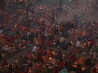 Hindu devotees sit together in front of oil lamps and pray to Shri Shri Loknath Brahmachari, a Hindu saint and philosopher, as they observe...