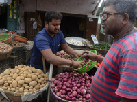 An Indian seller attends to customers while selling onions at his roadside shop in Siliguri, India, on November 16, 2024. Onion prices in th...