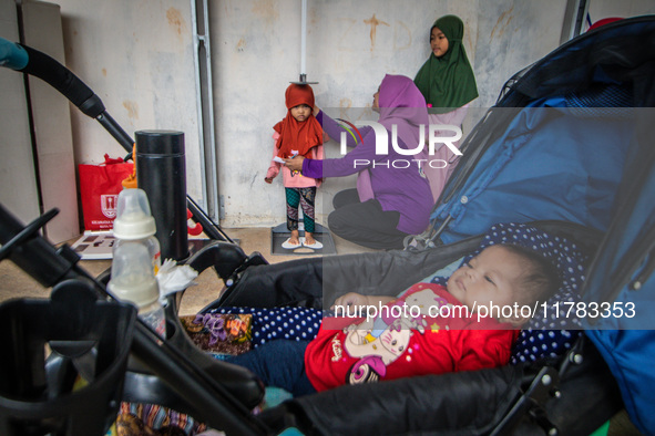 A child is measured during a child stunting prevention program at an integrated services post (POSYANDU) at Perum Panorama Asri in Kalongan...