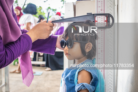 A child is measured during a child stunting prevention program at an integrated services post (POSYANDU) at Perum Panorama Asri in Kalongan...