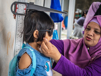 A child is measured during a child stunting prevention program at an integrated services post (POSYANDU) at Perum Panorama Asri in Kalongan...