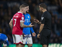 Referee Thomas Kirk talks to James McClean #7 of Wrexham A.F.C. during the Sky Bet League 1 match between Stockport County and Wrexham at th...