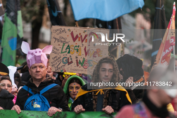 People wear animal masks and hold signs and banners as they participate in the street parade for the Climate Pride on November 16, 2024 in R...